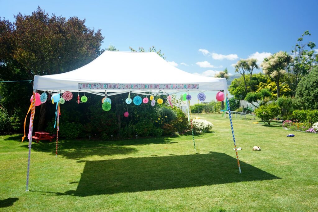 Weißer Gartenpavillon mit Happy-Birthday-Dekoration und bunten Girlanden