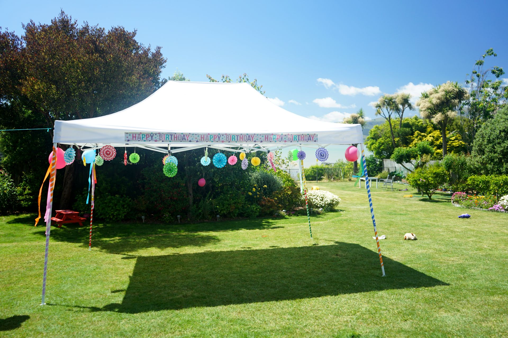 Weißer Gartenpavillon mit Happy-Birthday-Dekoration und bunten Girlanden